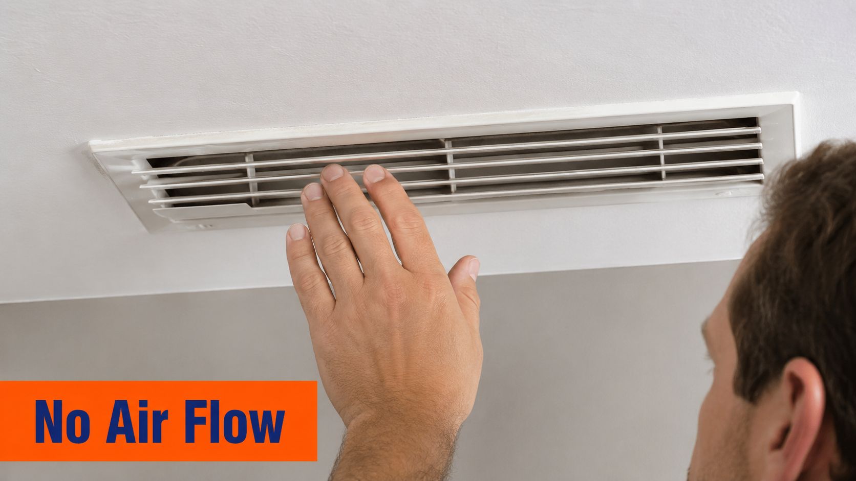 A man checking a ceiling air conditioning vent for airflow with his hand, indicating no air movement.